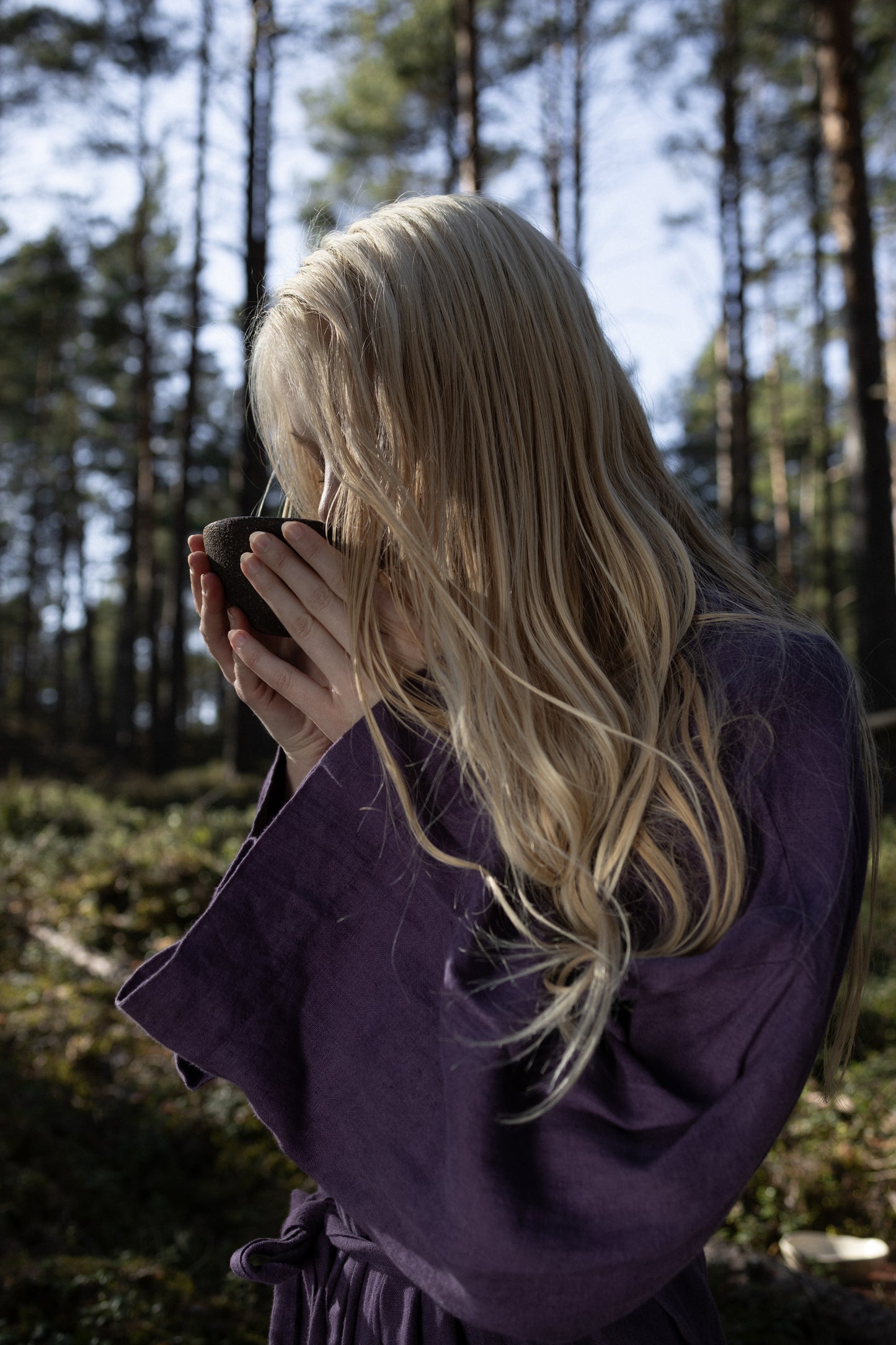 A girl drinking AGASAGA forest herbal tea in the forest.